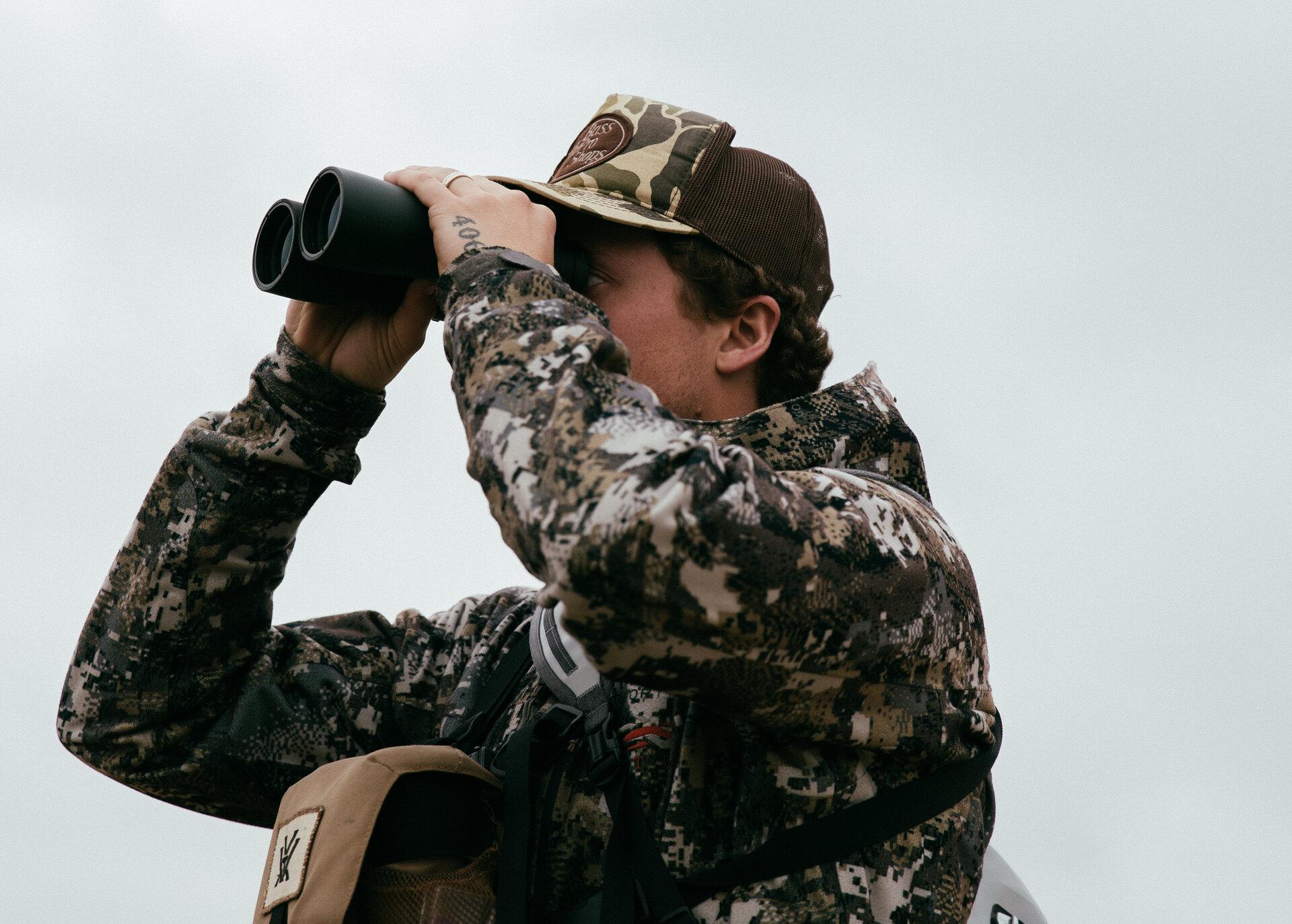 Hunter glassing with binoculars on leased land